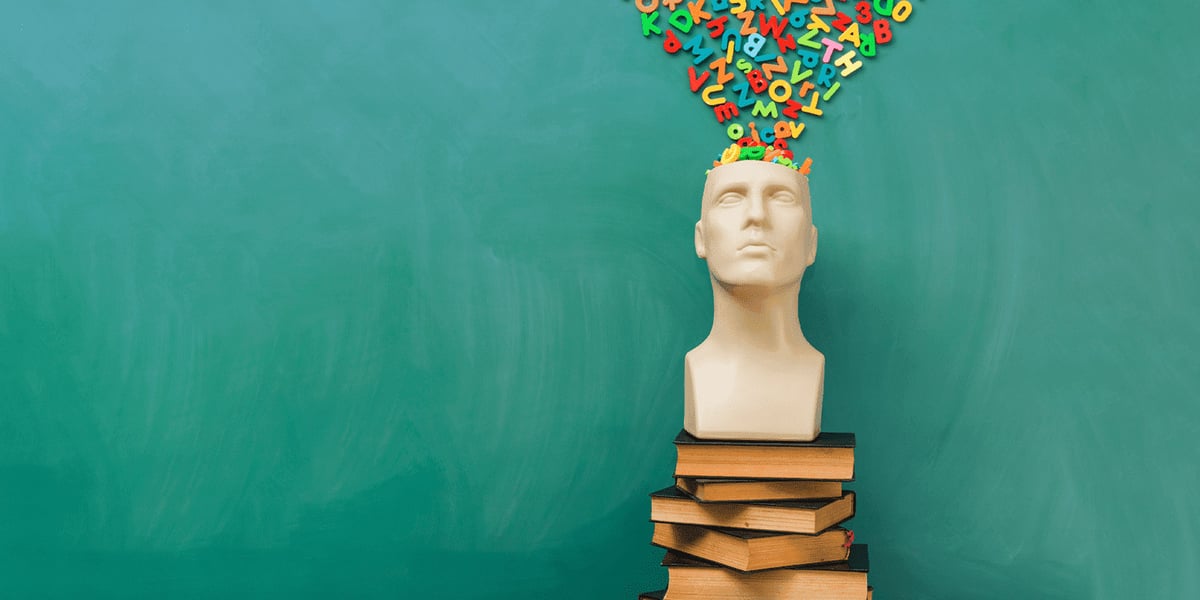 Mannequin-head filled with letters on a stack of books 